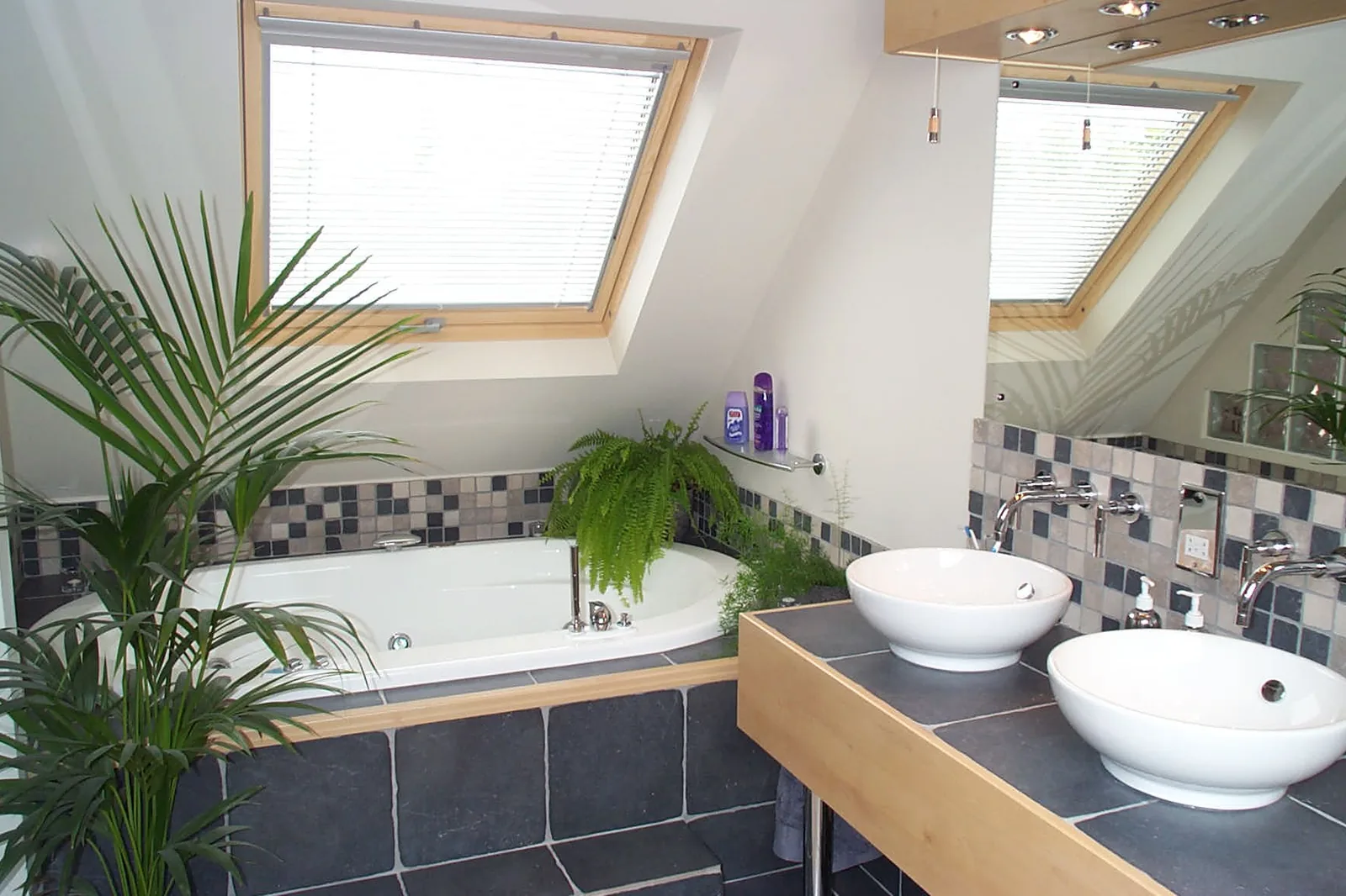 Loft en-suite bathroom with pine-framed roof windows and a corner bath